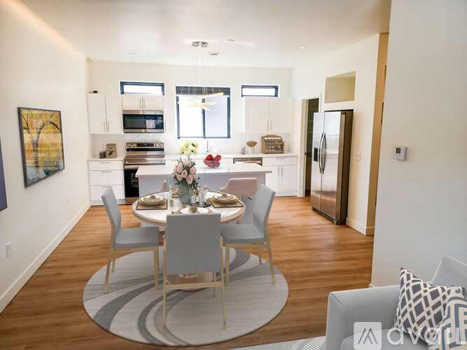 A modern dining room with a round table and grey chairs.