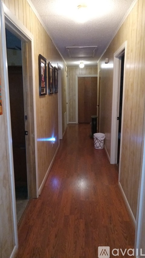 A long hallway with a trash can and pictures on the wall.