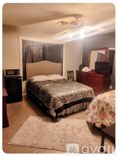 A bedroom with a bed, dresser, and ceiling fan.