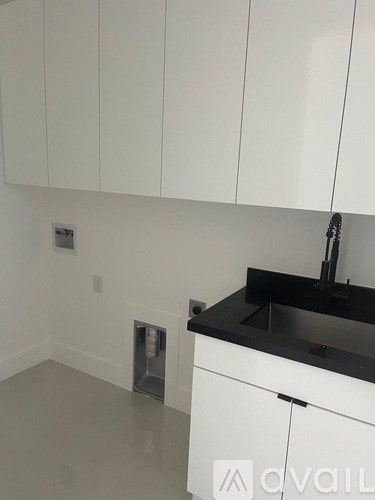 A kitchen with white cabinets and a black countertop.
