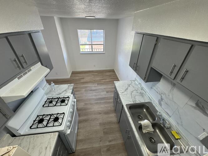 A kitchen with a stove, sink, and cabinets.