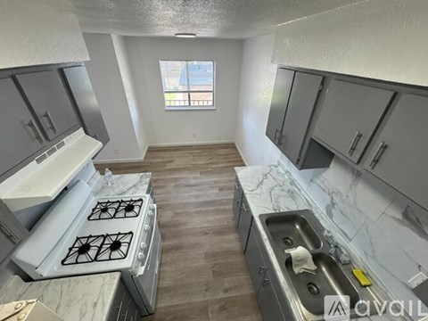 A kitchen with a stove, sink, and cabinets.