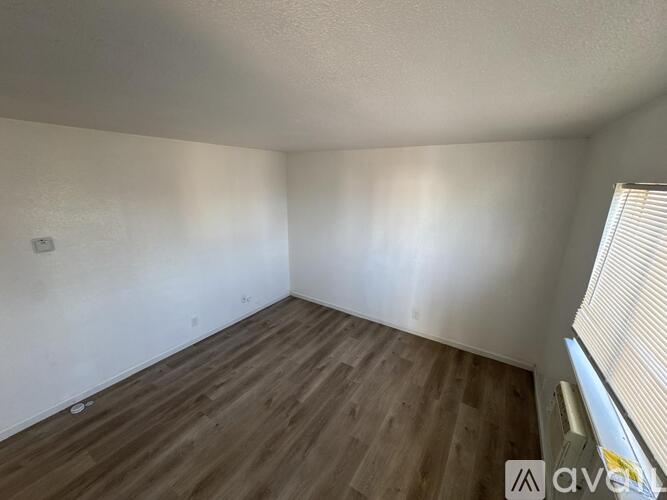 A room with wooden flooring and a window with blinds.