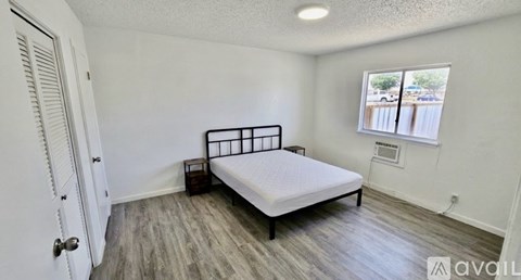 A bedroom with a bed, nightstand, and window.