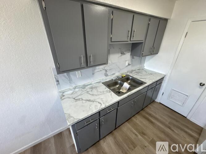 A kitchen with grey cabinets and a marble countertop.