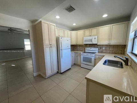 A kitchen with a refrigerator, sink, and cabinets.