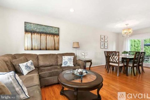 A living room with a brown couch, a coffee table, and a painting on the wall.