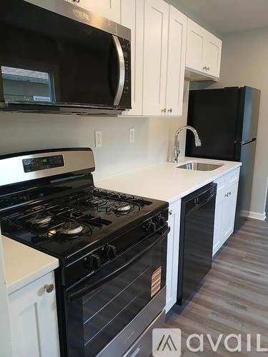 A kitchen with a black stove top oven and white cabinets.