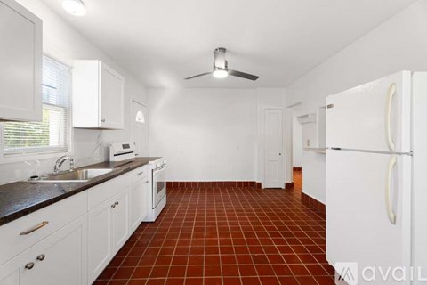 A kitchen with white cabinets and a black countertop.