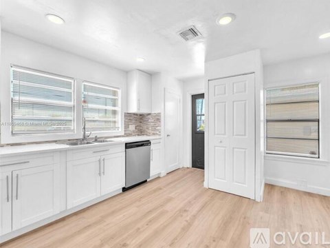 A kitchen with white cabinets and a wooden floor.