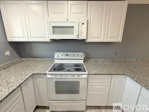 A kitchen with white cabinets and a granite countertop.