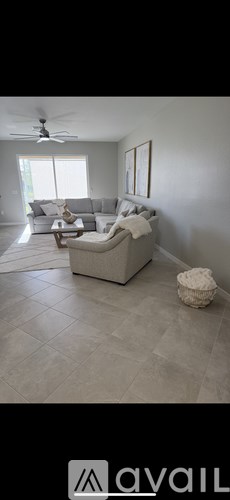 A living room with a grey couch and a ceiling fan.