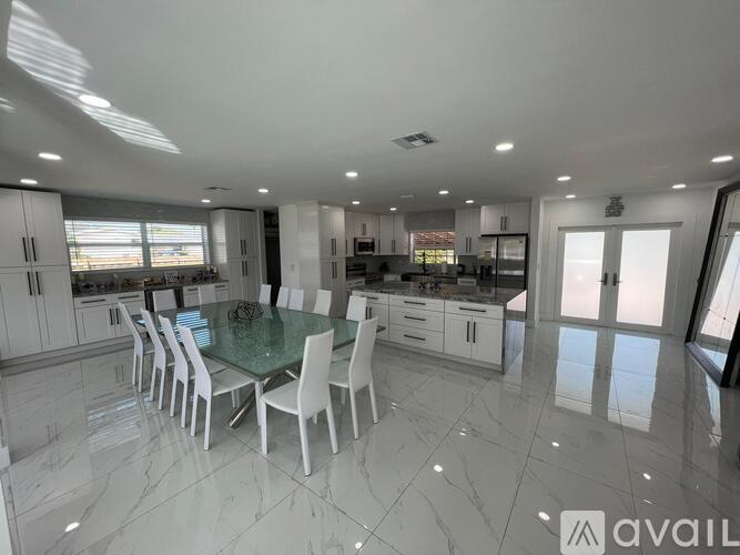 A spacious kitchen with a glass table and white chairs.