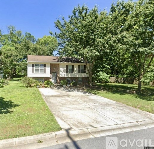 A house with a driveway and trees in the background.