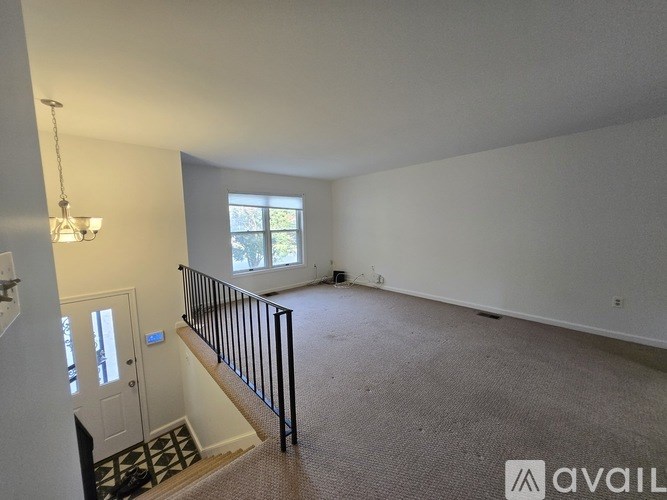 A spacious room with a carpeted floor and a window with blinds.