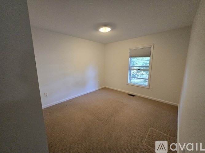 A room with a window and carpeted floor.