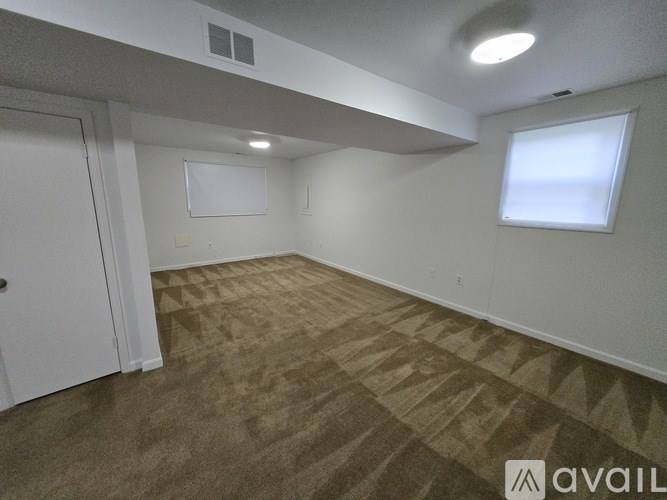 A room with a carpeted floor and a door on the left side.