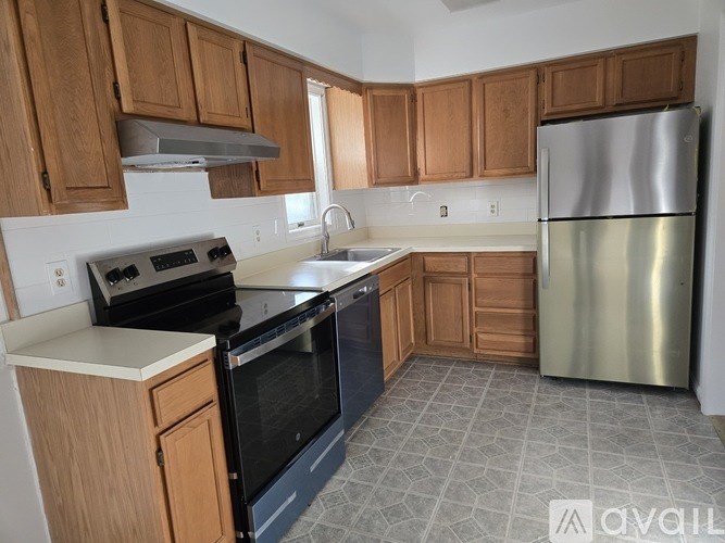 A kitchen with wooden cabinets and a stainless steel refrigerator.