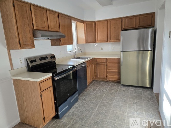 A kitchen with wooden cabinets and a stainless steel refrigerator.