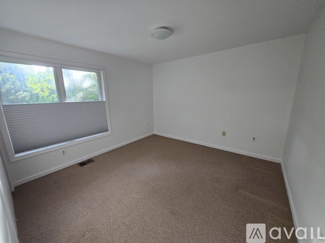 A room with a carpeted floor and a window with blinds.