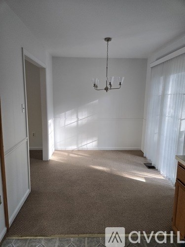 A large, empty room with a chandelier and a carpeted floor.