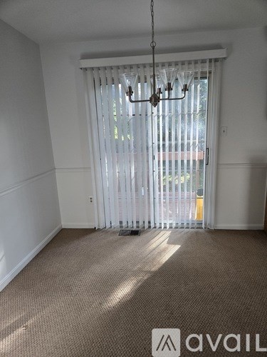 A room with a carpeted floor and a chandelier hanging from the ceiling.