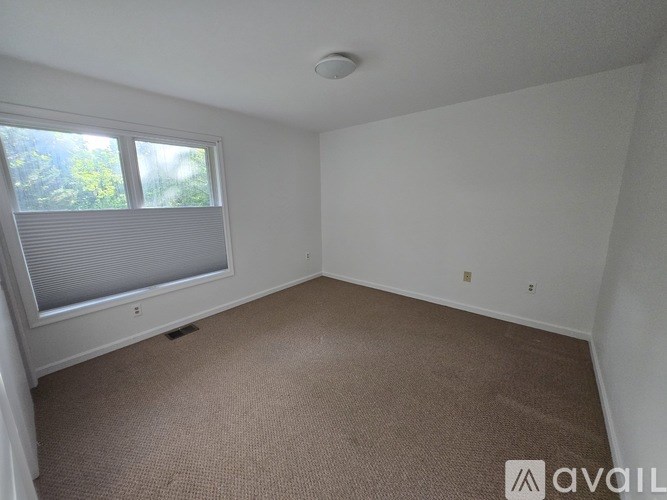 A room with a carpeted floor and a window with blinds.