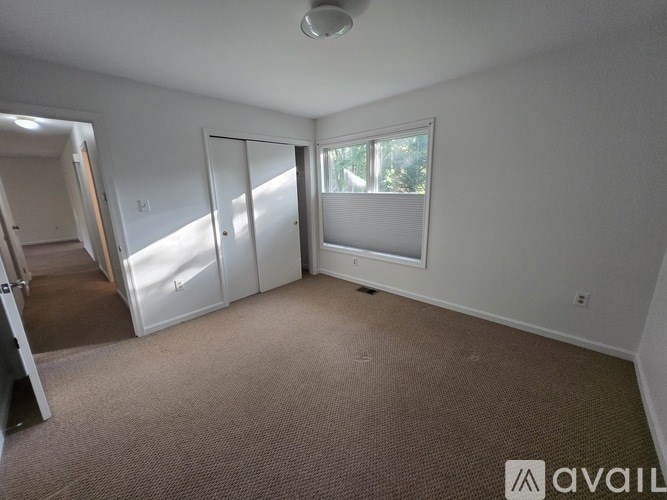 A carpeted room with a sliding door and a window.