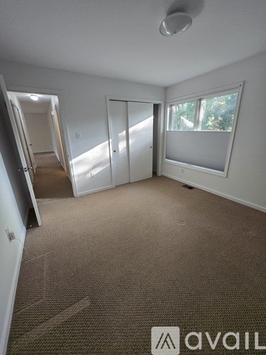 A carpeted room with a sliding door and a window.