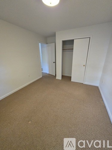 A carpeted room with a door on the right and a window on the left.