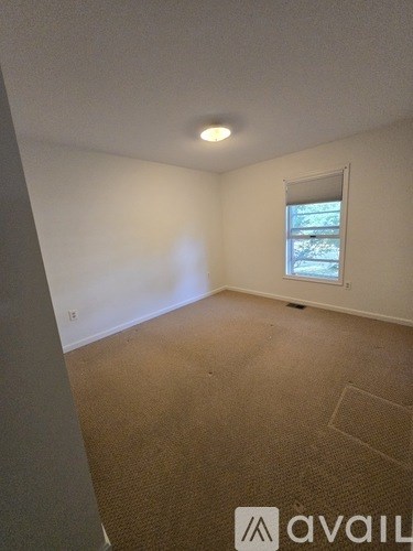 A room with a window and carpeted floor.