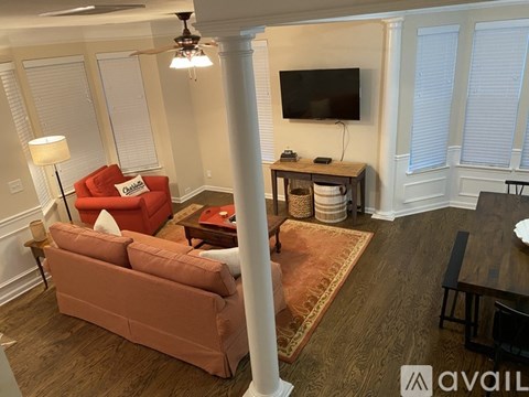 A living room with a red couch and a television on the wall.
