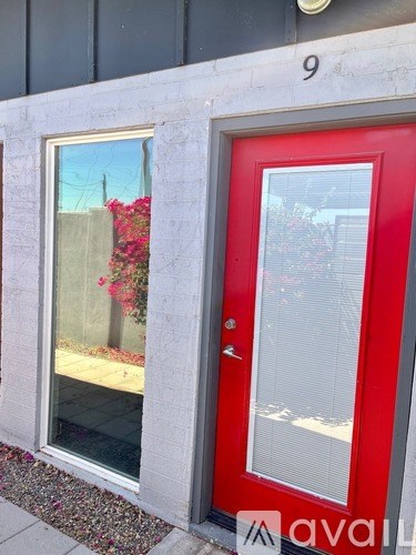 A red door with a glass window is on the side of a building.