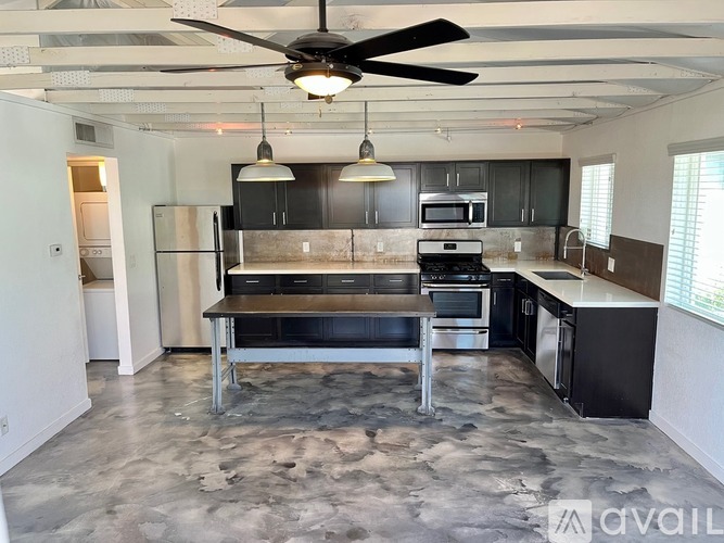 A kitchen with a black and white color scheme and a ceiling fan.