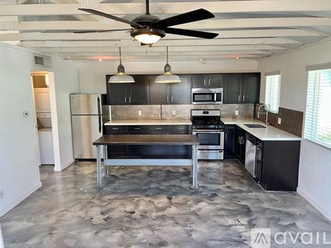 A kitchen with a black and white color scheme and a ceiling fan.
