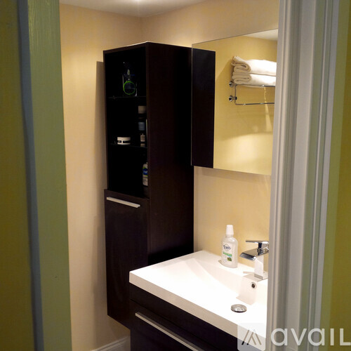 A bathroom with a white counter and a brown cabinet.