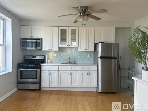A kitchen with white cabinets and a stainless steel refrigerator.