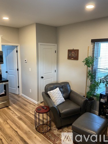 A living room with a black leather couch and a small table.