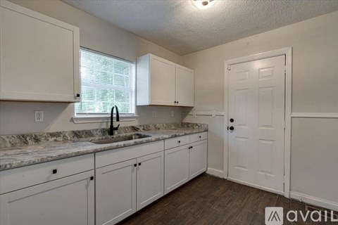A kitchen with white cabinets and a sink.