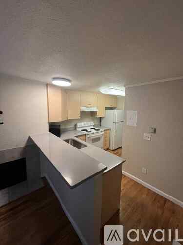 A kitchen with a white counter top and wooden cabinets.