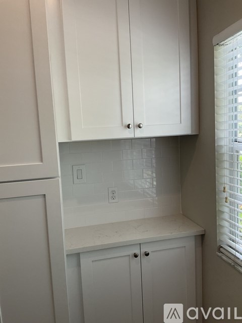 A kitchen with white cabinets and a window.