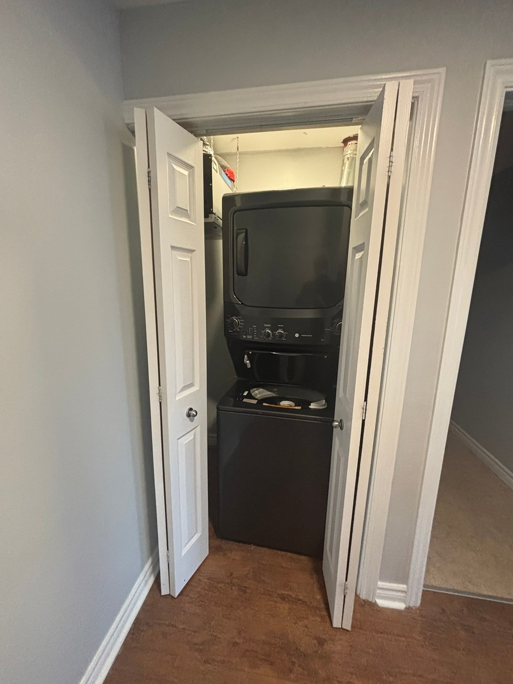 A black microwave and oven are installed in a cabinet under a door.