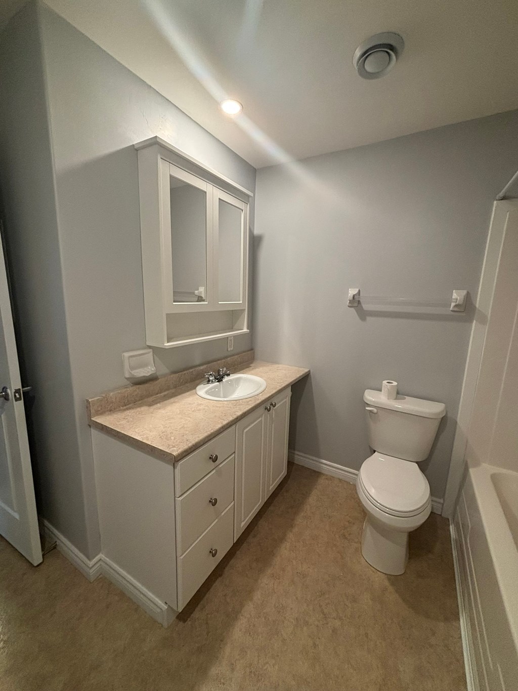 A bathroom with a toilet, sink, and medicine cabinet.