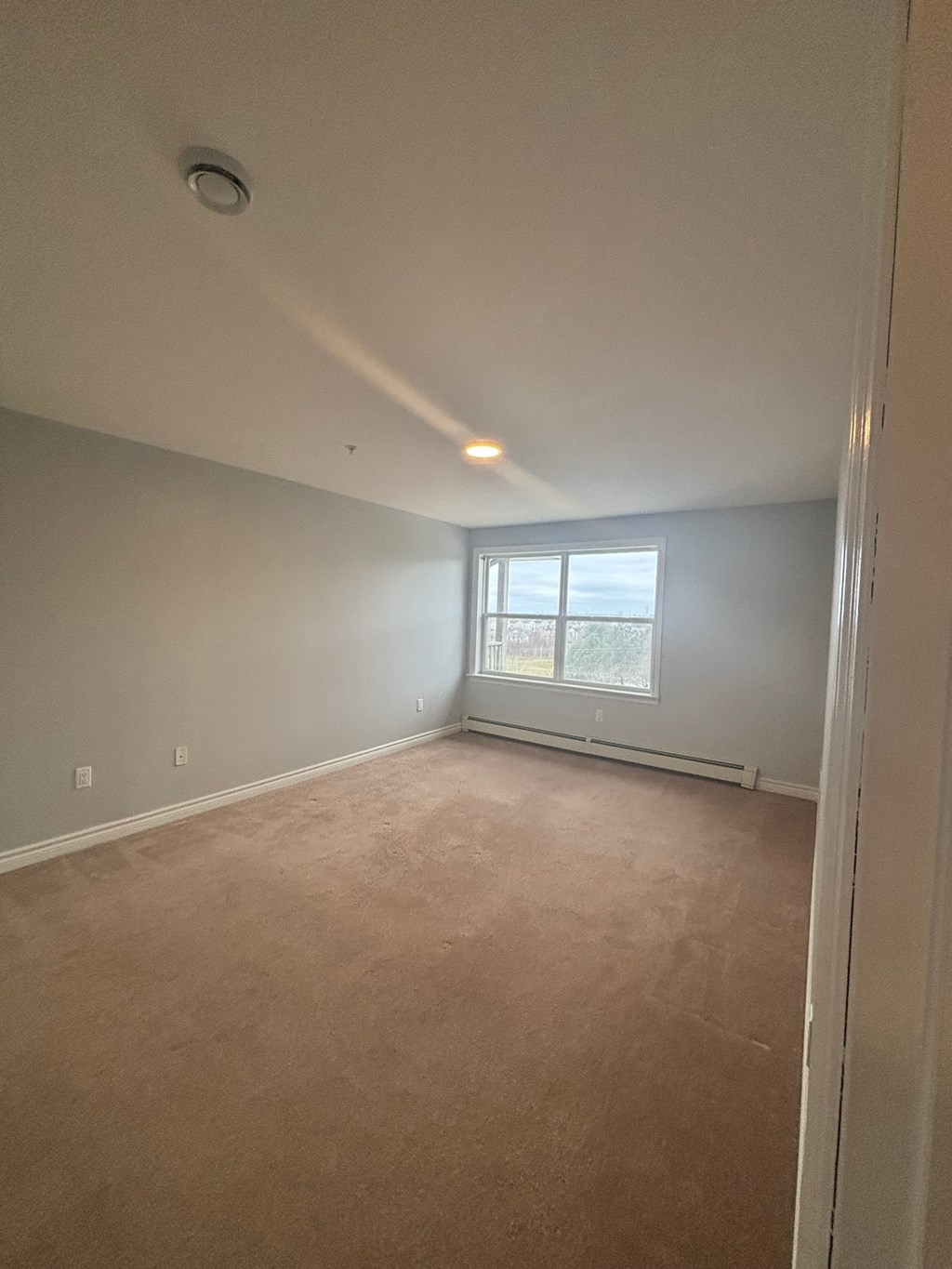 A room with a window and carpeted floor.