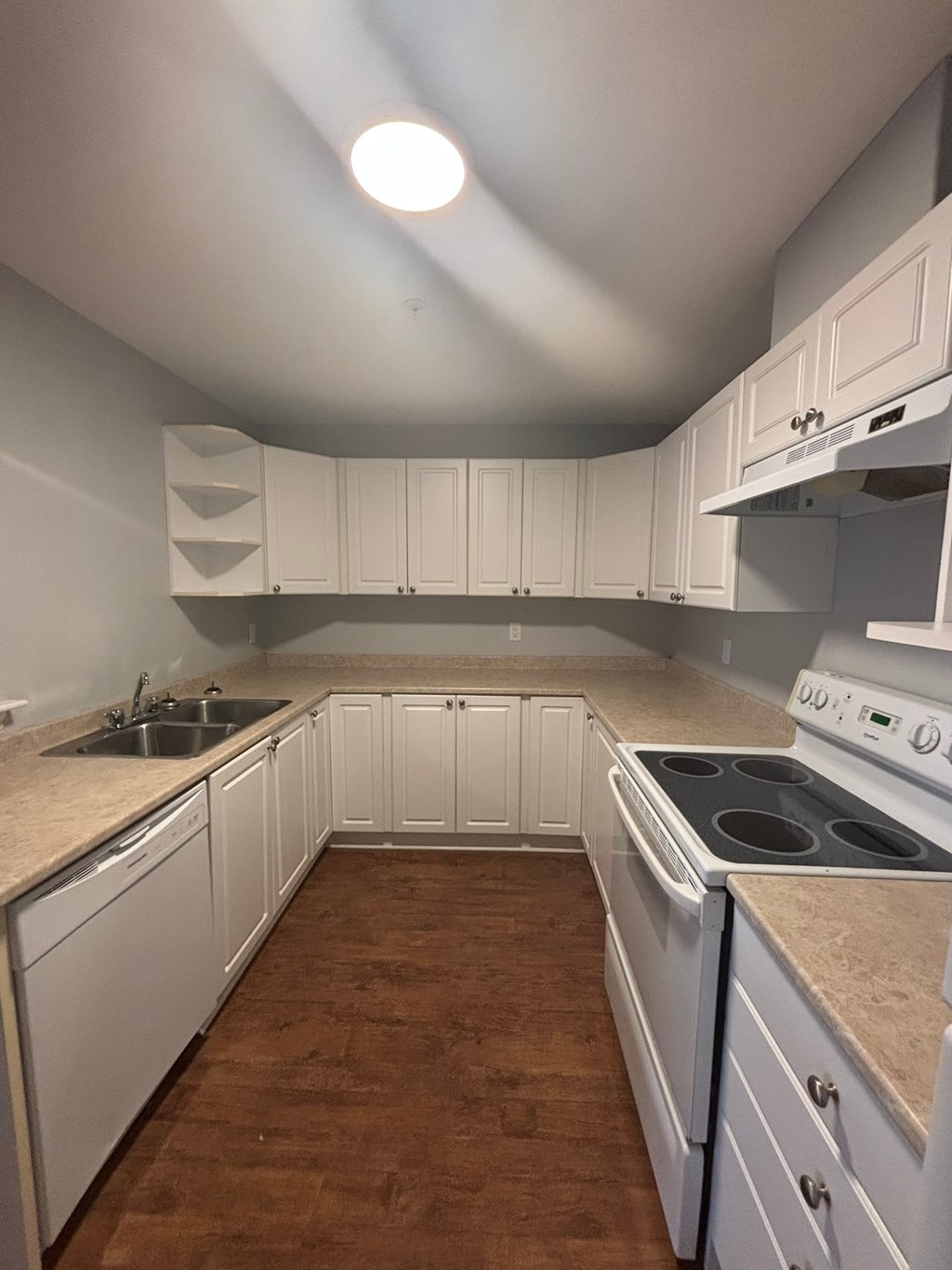 A kitchen with white cabinets and a stove top oven.