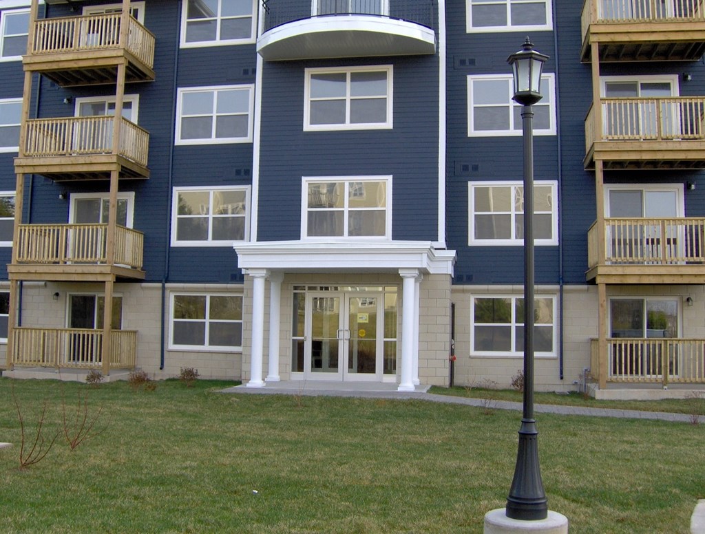 A blue apartment building with a white door and a lamp post in front.