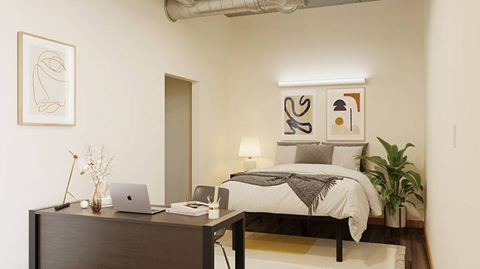 A bedroom with a bed, desk, and chair.