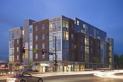 A multi-story building with a parking lot in front of it.