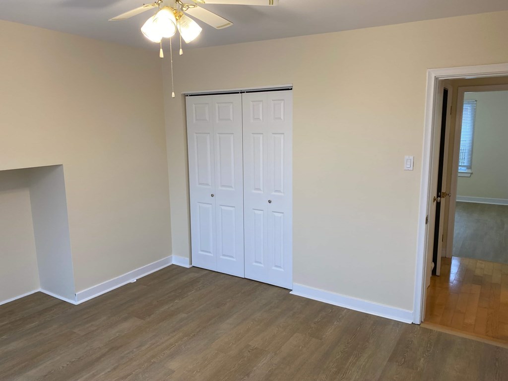 A room with a white door and a ceiling fan.