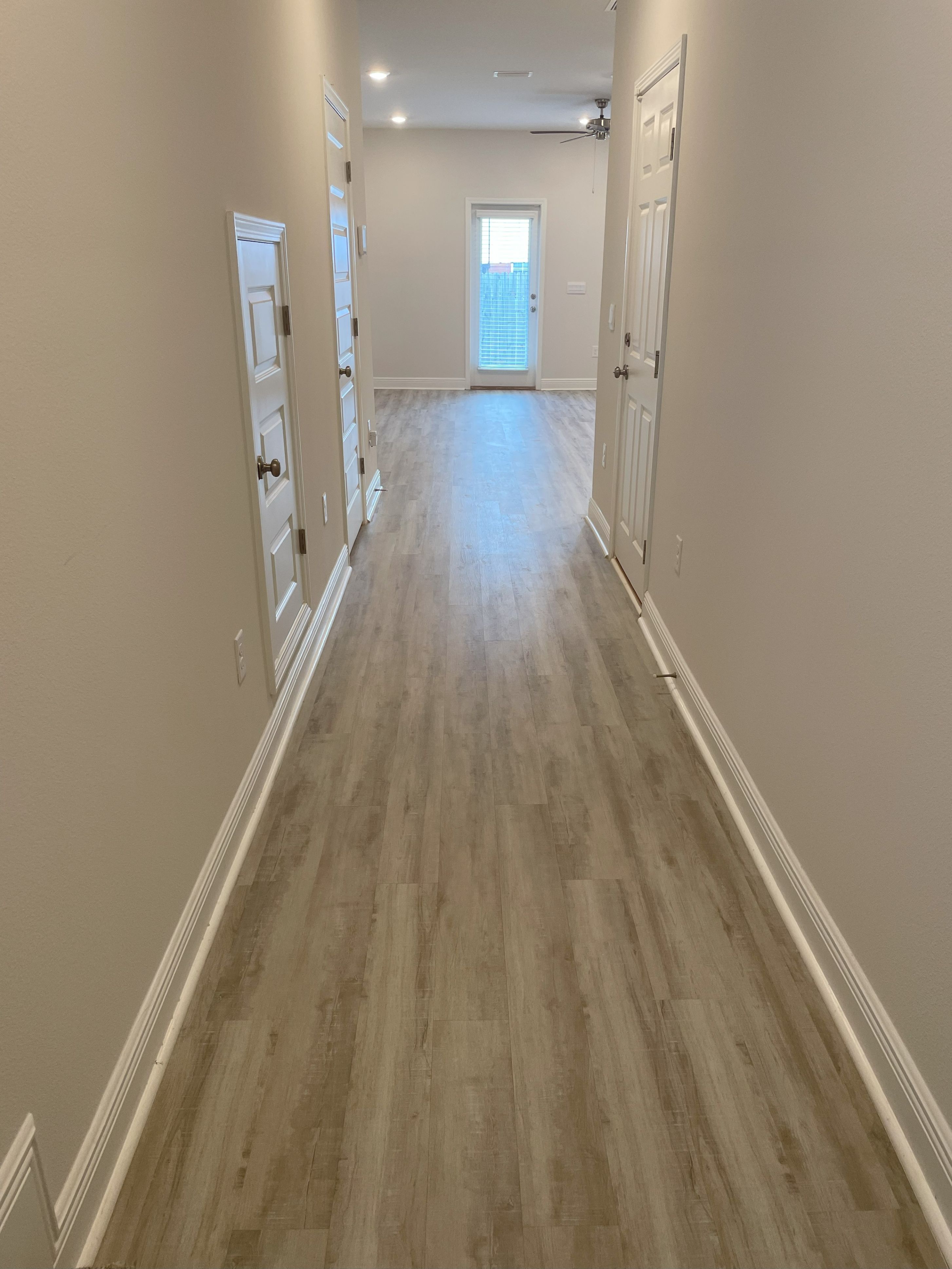 A long hallway with wood floors and white walls.